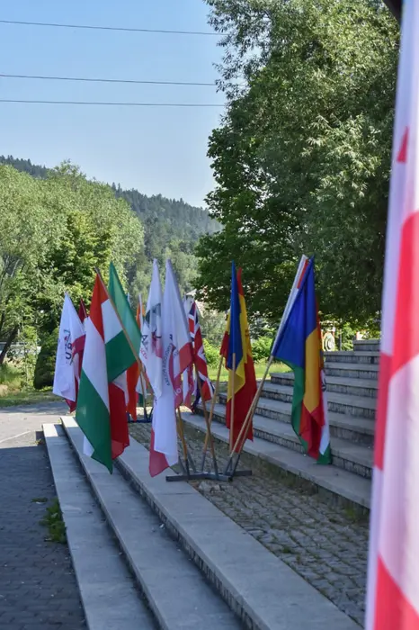 Drapelele țărilor participante, printre care și cel al României, aliniate la intrarea în locul de desfășurare
