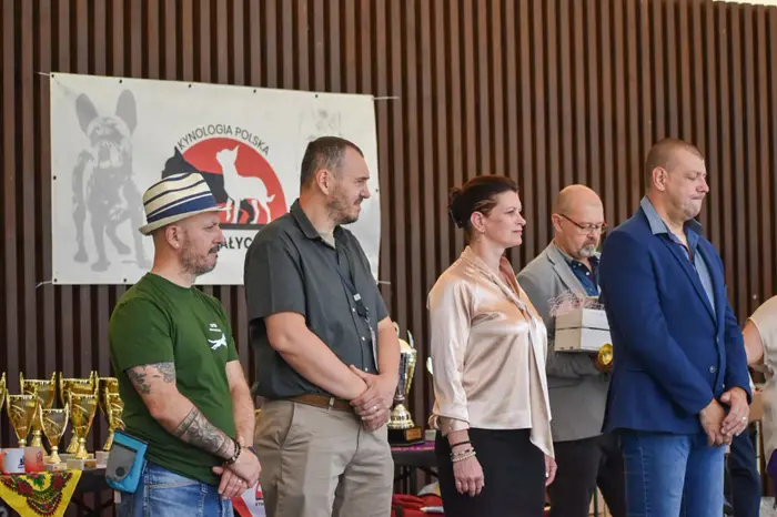 Arbitrii și oficialii evenimentului, în sală, sub bannerul Kynologia Polska